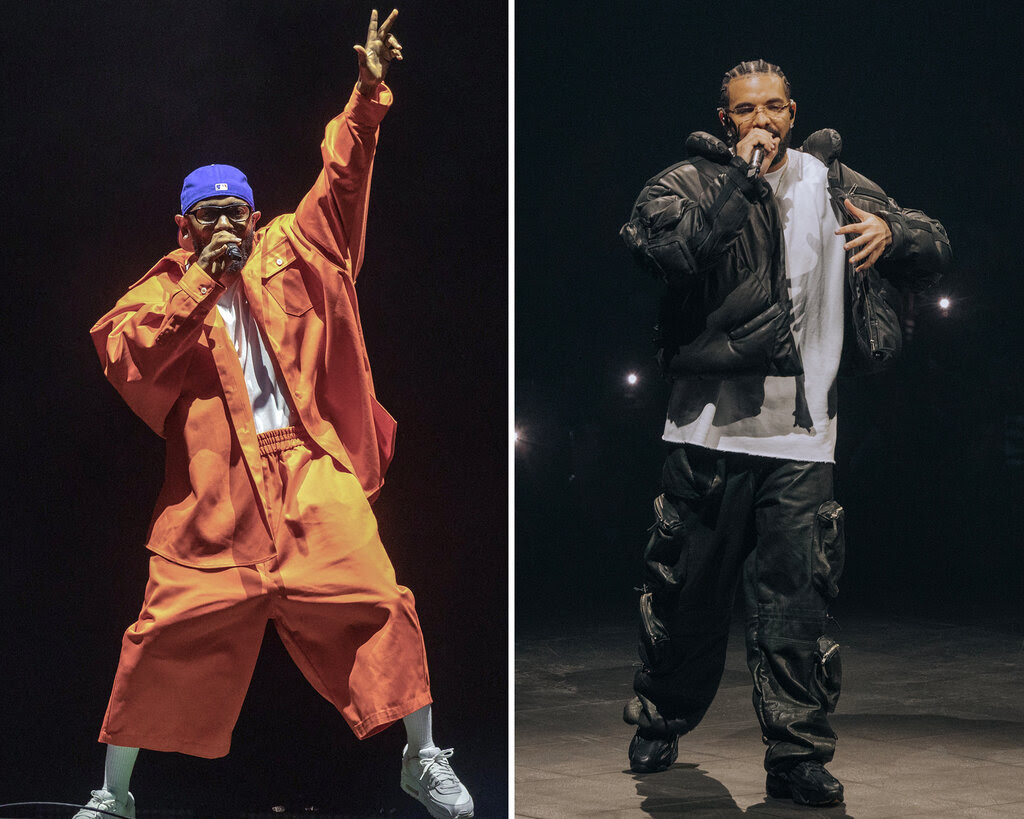 Kendrick Lamar dressed in an orange suite and Drake dressed in a white t-shirt and black jacket and pants. 