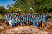 GulfCorps members pose as a large group in blue t-shirts on a sunny day