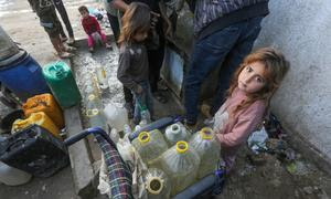 Una niña espera para llenar contenedores de agua en Gaza.