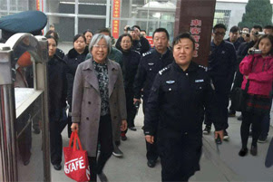 Yang Rongli is smiling. She is surrounded by group of people, many of whom are holding cameras.