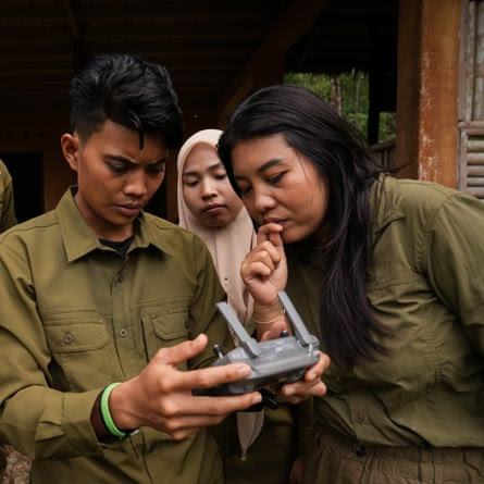 A man demonstrates how to use a drone control to two women