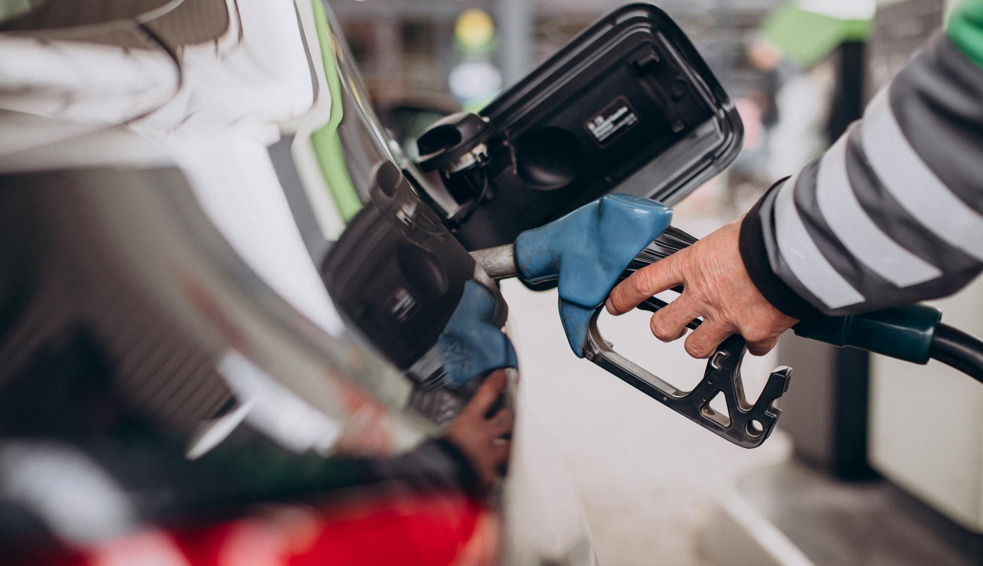 Persona repostando combustible en un automóvil en una estación de servicio, utilizando una manguera