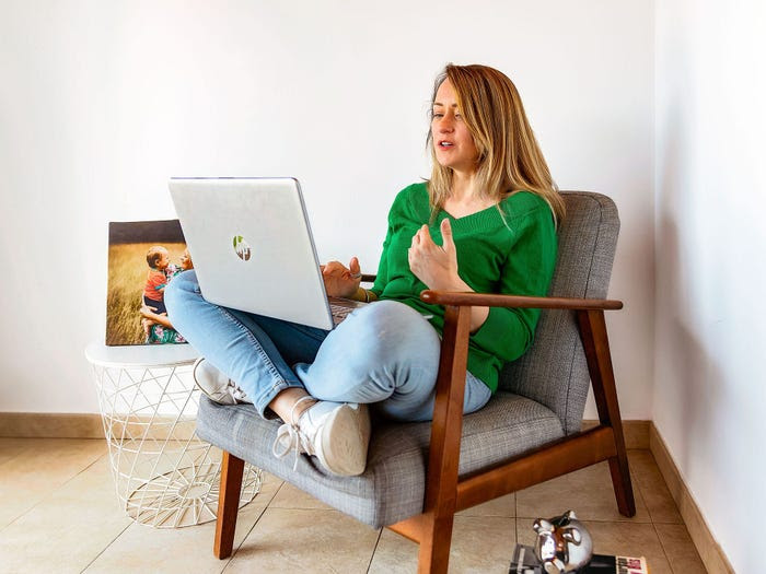 Woman in a green sweater sitting on a chair with a laptop
