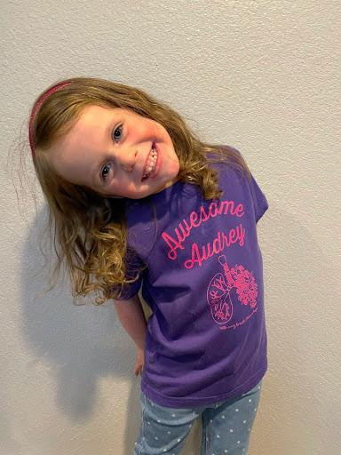 photo of little girl in a purple shirt with a big smile.