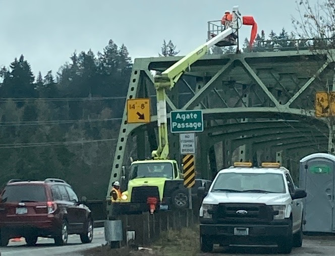 Road crews working on a bridge taking up one of the two lanes of traffic