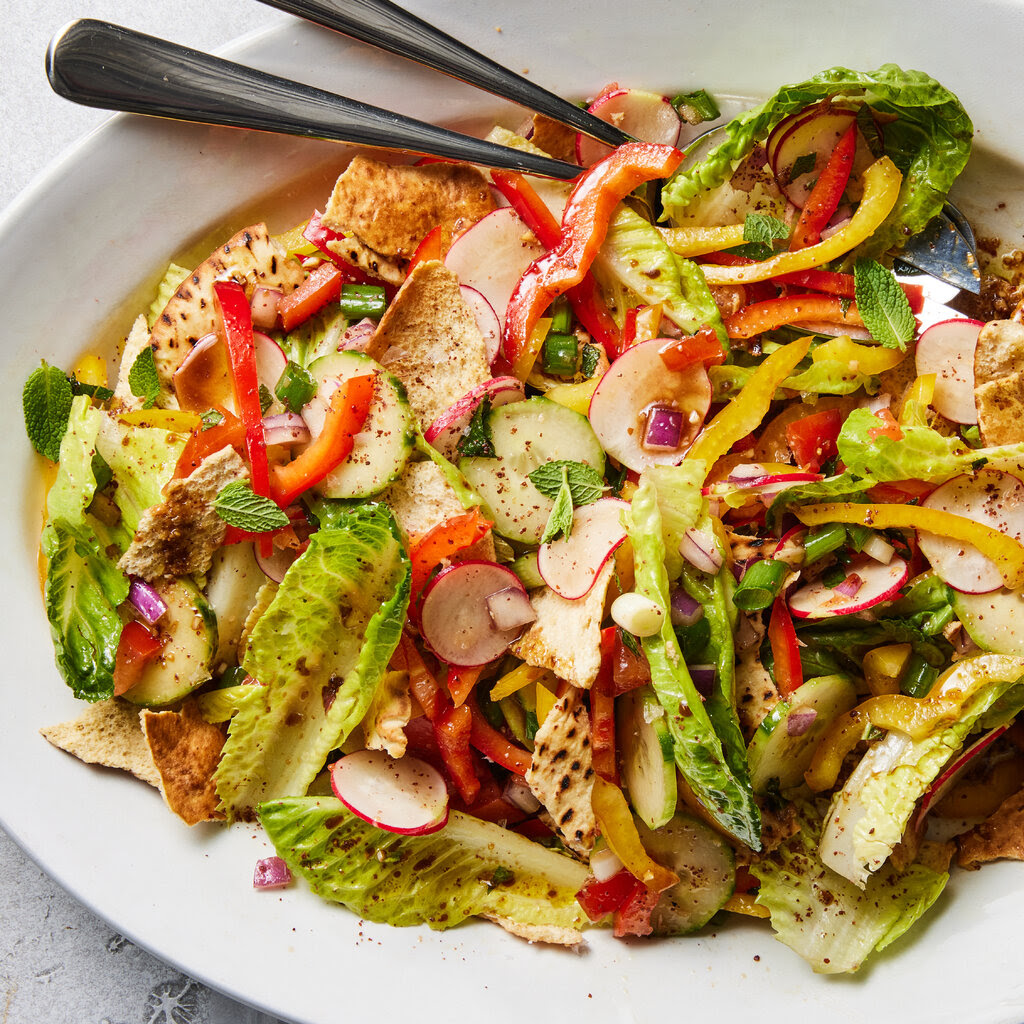 A salad with pita, tomatoes, peppers and other ingredients.