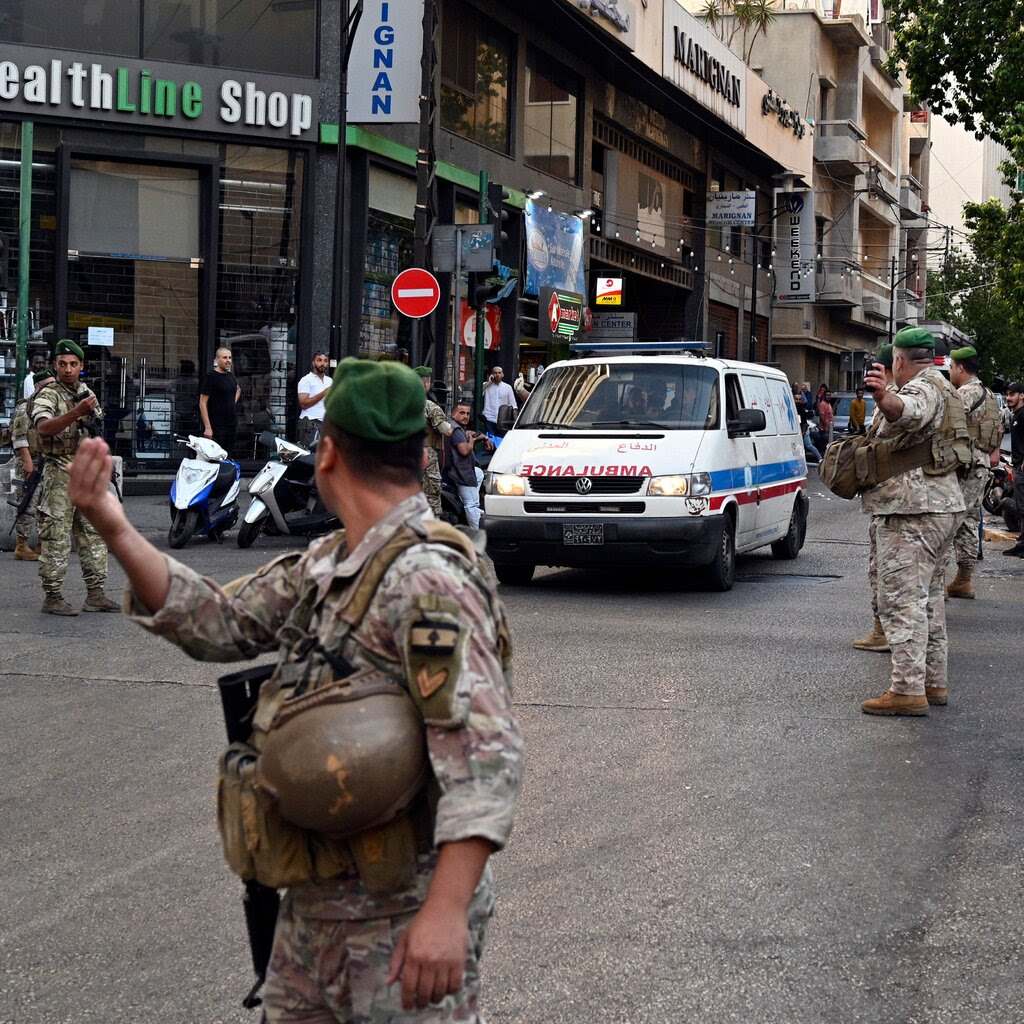 Soldiers clear a street in an urban area for an ambulance to pass through.