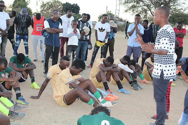 Pastor Edward Muchengaguyo (right front) leads a prayer following a soccer match between Hwedza United and the Dendenyore Red Stars in Wedza, Zimbabwe. Muchengaguyo, newly appointed to St. James Hwedza United Methodist Church, is using sports to bring young people to Christ. Photo by Kudzai Chingwe, UM News.