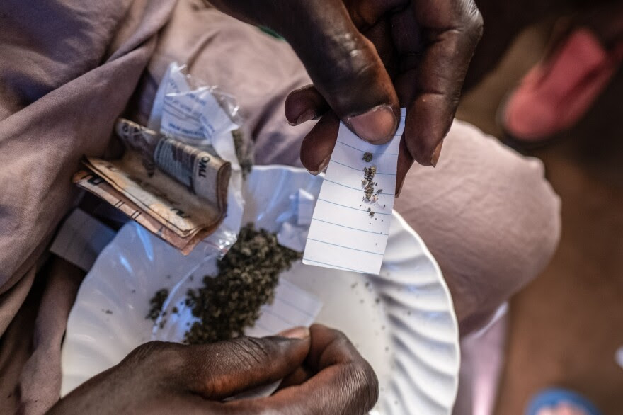 A kush dealer measures out a portion of kush, which will be wrapped in a paper packet and sold for as little as 5,000 Leones (roughly $0.25), in Freetown, Sierra Leone.