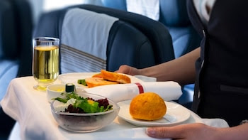 Azafata sirviendo comida en un avión (Shutterstock).