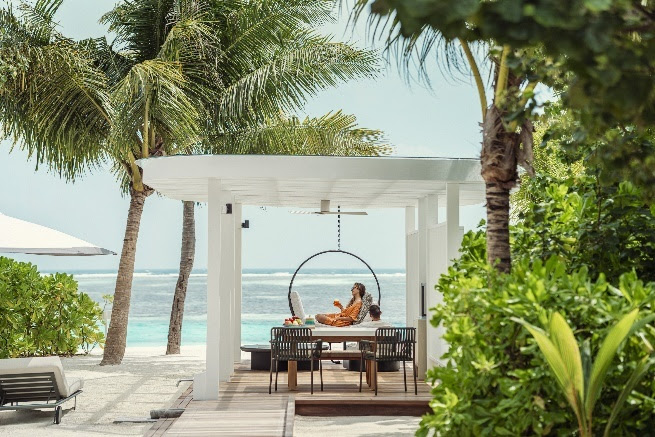 A person sitting in a chair under a canopy on a beachAI-generated content may be incorrect.