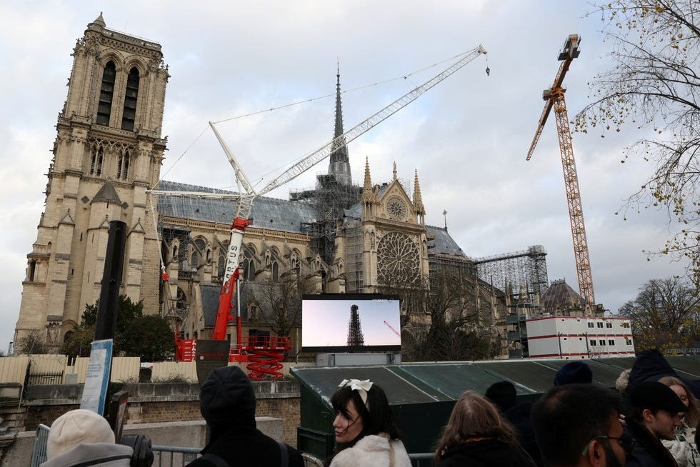 La gente se para frente a una pantalla en un área pública para ver la ceremonia de reapertura de la Catedral de Notre-Dame en París, Francia, el 7 de diciembre de 2024.