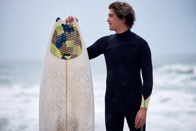 Beach athlete and man with a surfboard on a vacation summer adventure or trip in Australia Fitness workout and surfer with a board by the ocean for water sports competition training or exercise