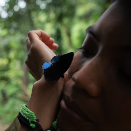 A woman with a moth resting on her hand next to her face