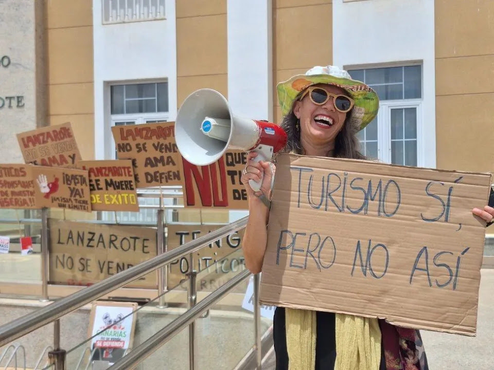 Manifestantes con un altoparlante y una pancarta que dice: Turismo sí, pero no así