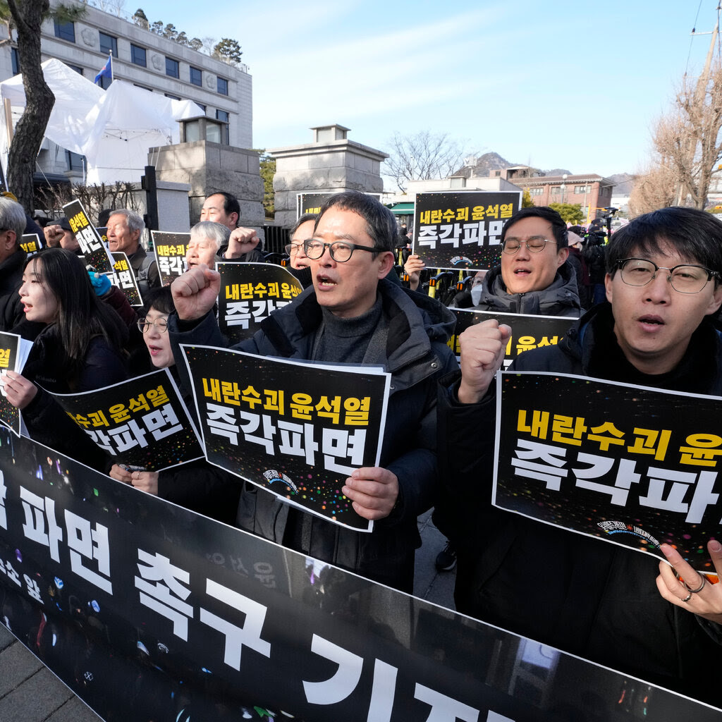 People dressed in black gathered behind a banner and held up protest signs 