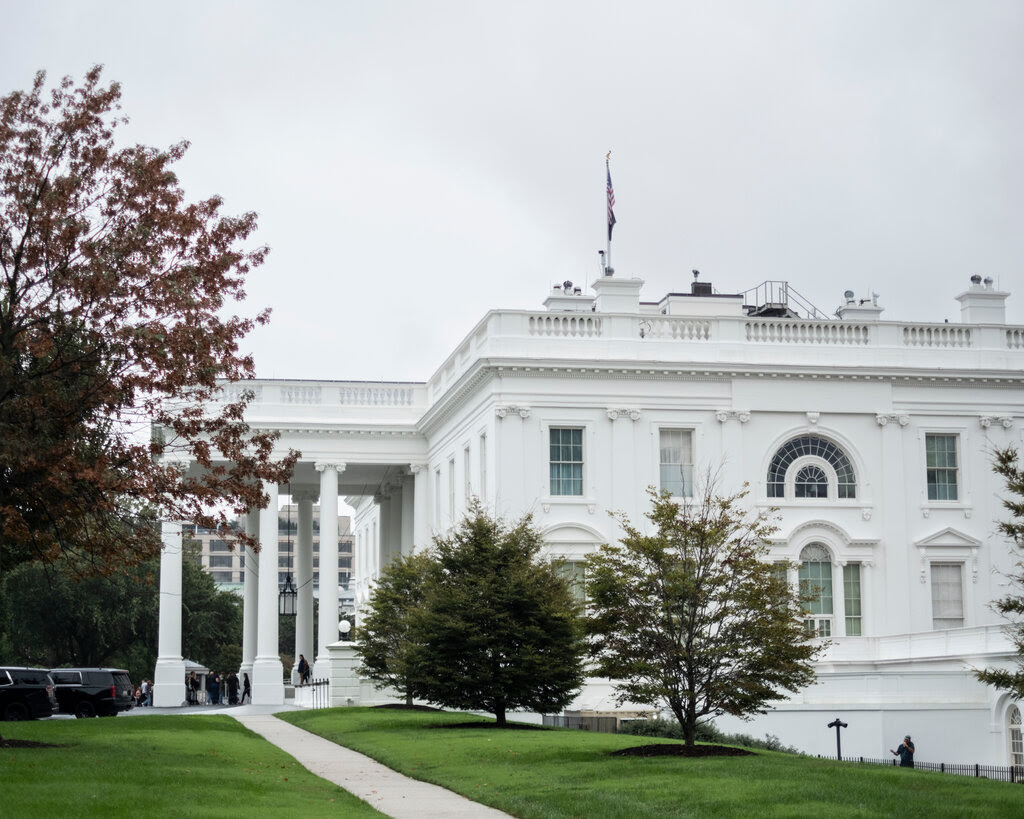 The White House, with black vehicles parked out front.