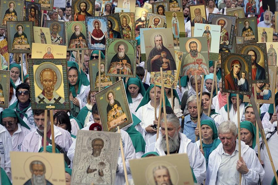 A procession of Orthodox Christians holding posters of Russian religious icons.