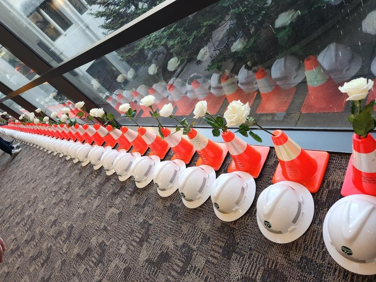 Line of traffic cones, hard hats and roses in a hallway in a building
