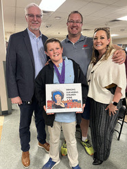 Mason McCarthy holds winning poster standing next his parents and CBI Assistant Director Kirby Lewis.