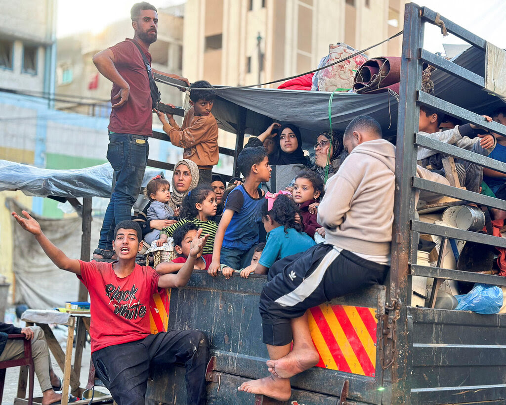 People sit in the back of a truck as they begin evacuating from the Gazan city of Rafa.