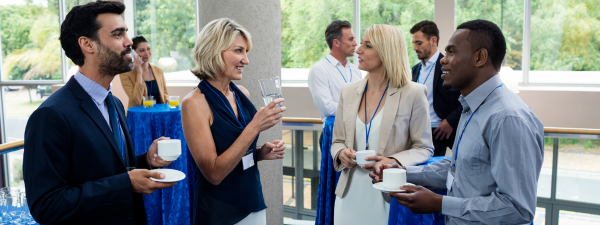 Diverse crowd of people holding coffee cups and chatting in a professional environment