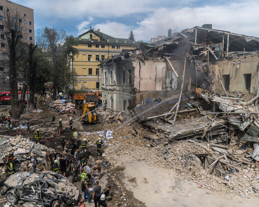 Firefighters spraying water in the rubble of a destroyed building.