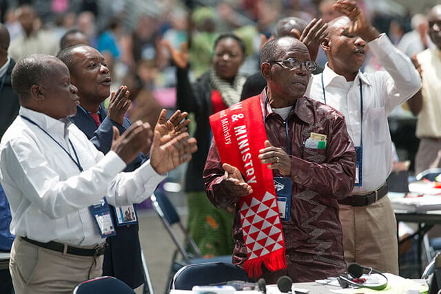 Michel Lodi of the East Congo Conference (right foreground) joins other African delegates in singing during a recess at the 2016 United Methodist General Conference in Portland, Ore. File photo by Mike DuBose, UM News. 