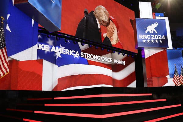 A photograph of the stage at the Republican National Convention. On the jumbotron, Peter Navarro kisses his fiancée.