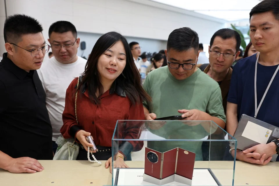 People look at Huawei's new tri-foldable smartphone Mate XT at a store in Beijing