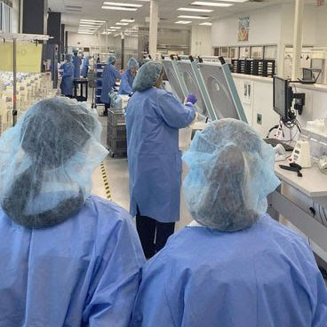 a group of students are dressed in scrubs, masks and hair nets and walk inside of a lab