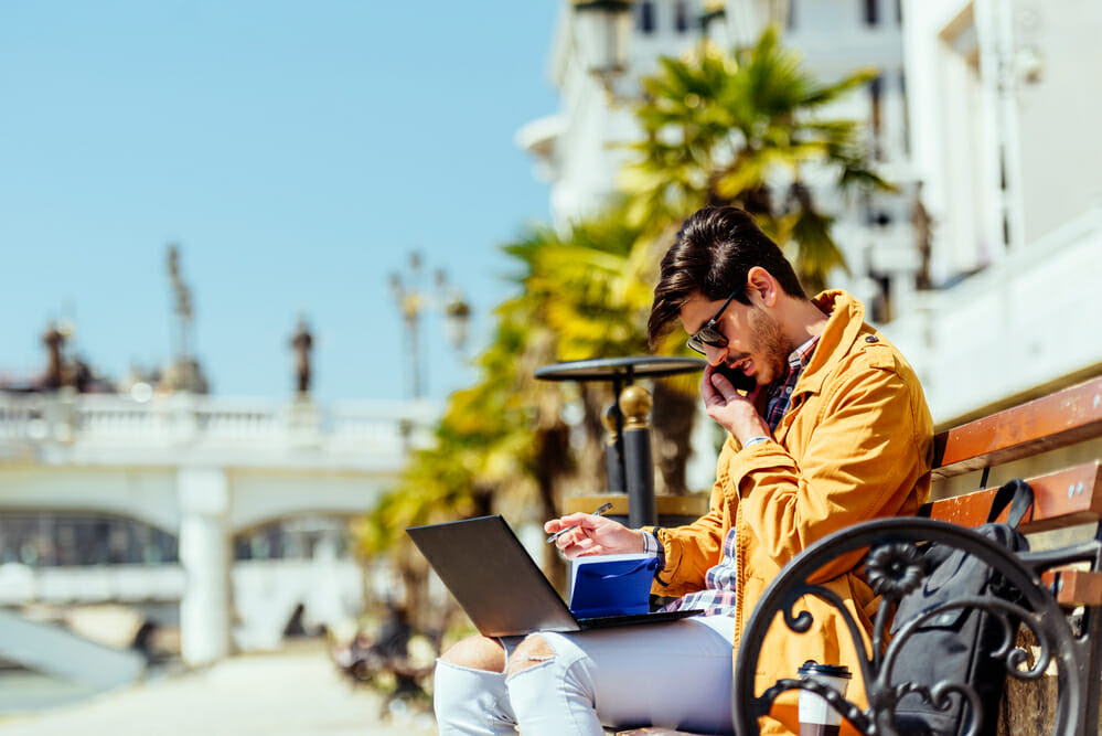 Young businessman work on laptop sitting on bench