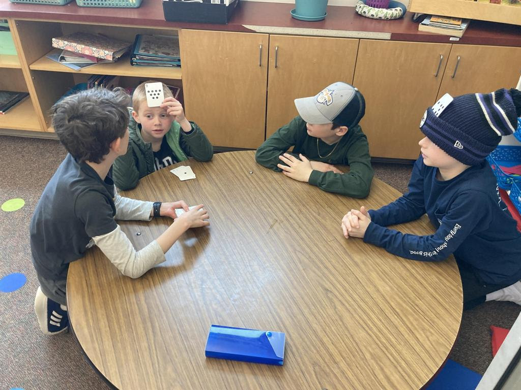 Four children sitting around a round table, playing a game and interacting.