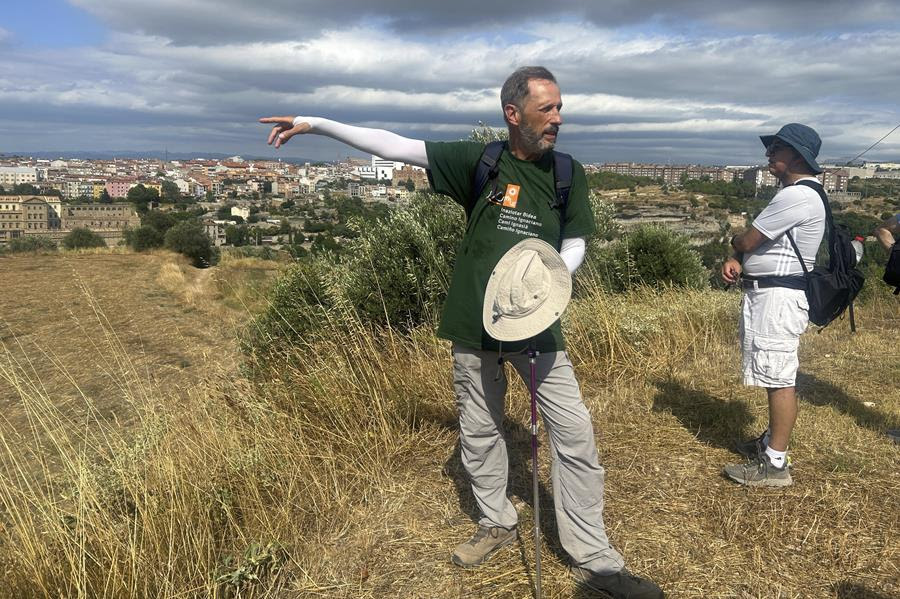 A man leads a tour through a field.