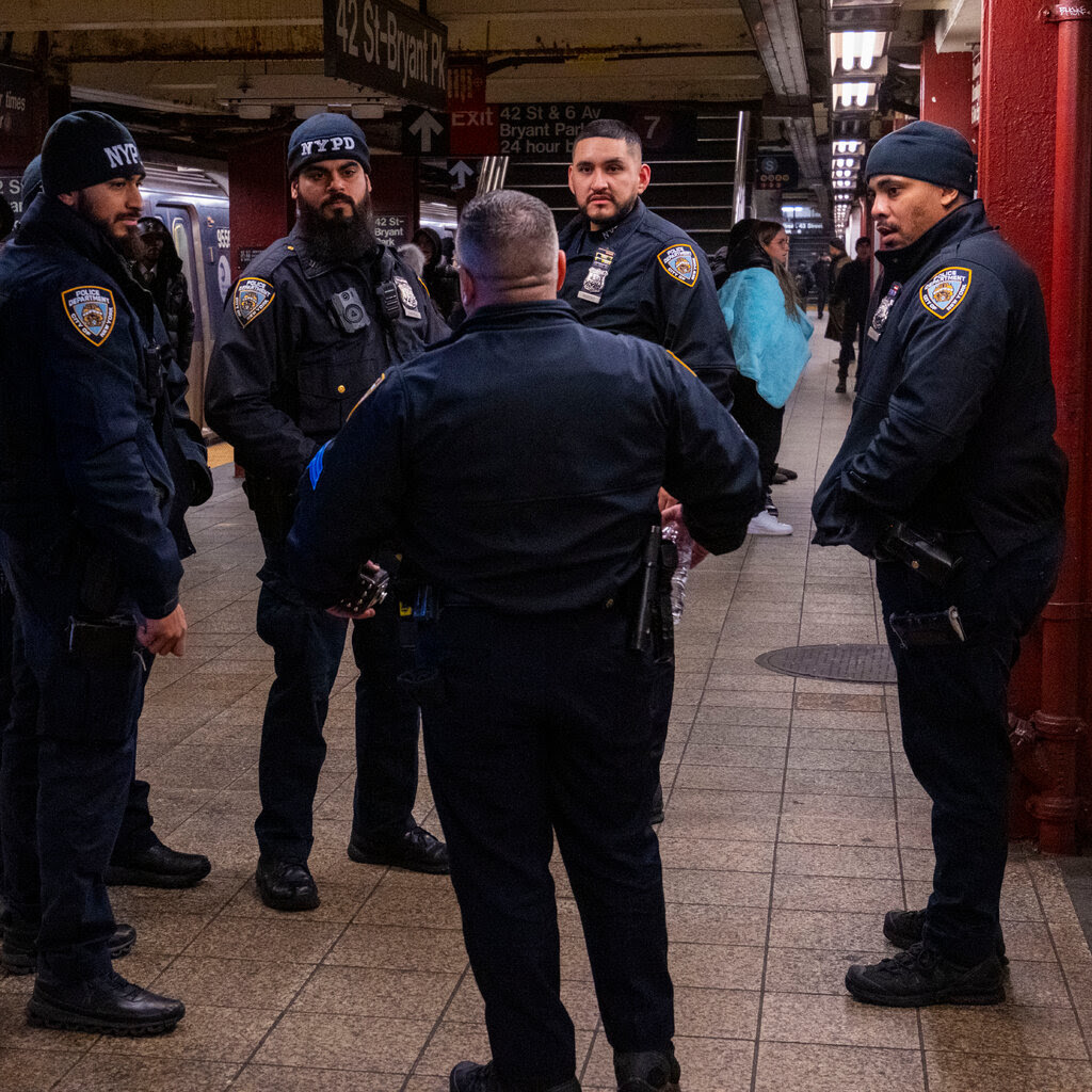 New York City police officers standing on a subway platform. 