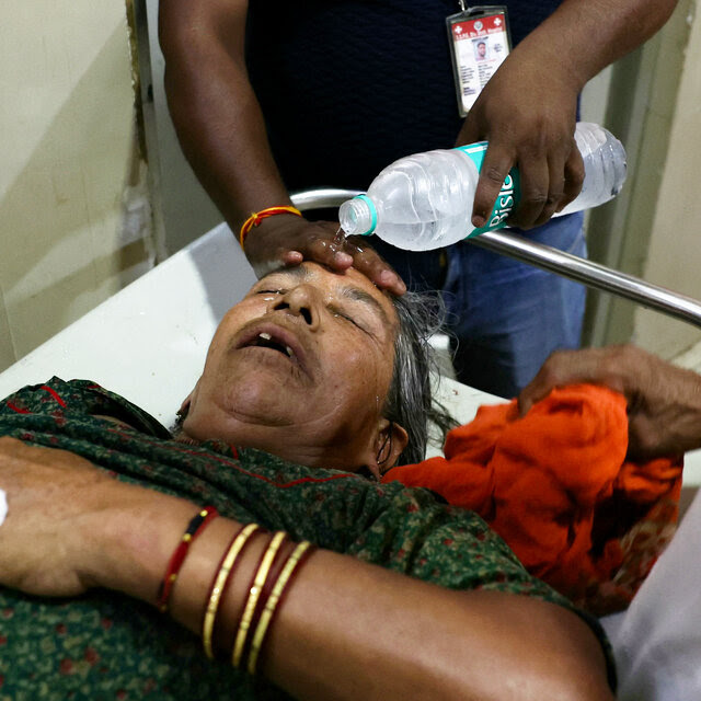 A hospital staff member pours water on the face of a patient suffering from heat stroke at a hospital.