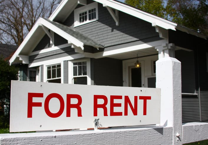 A For Rent sign in front of a house.