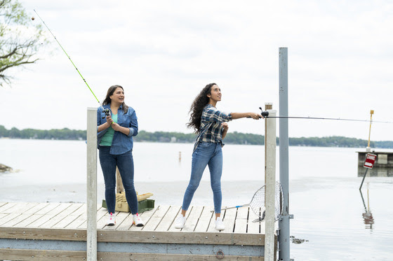 two women holding fishing rods on a dock