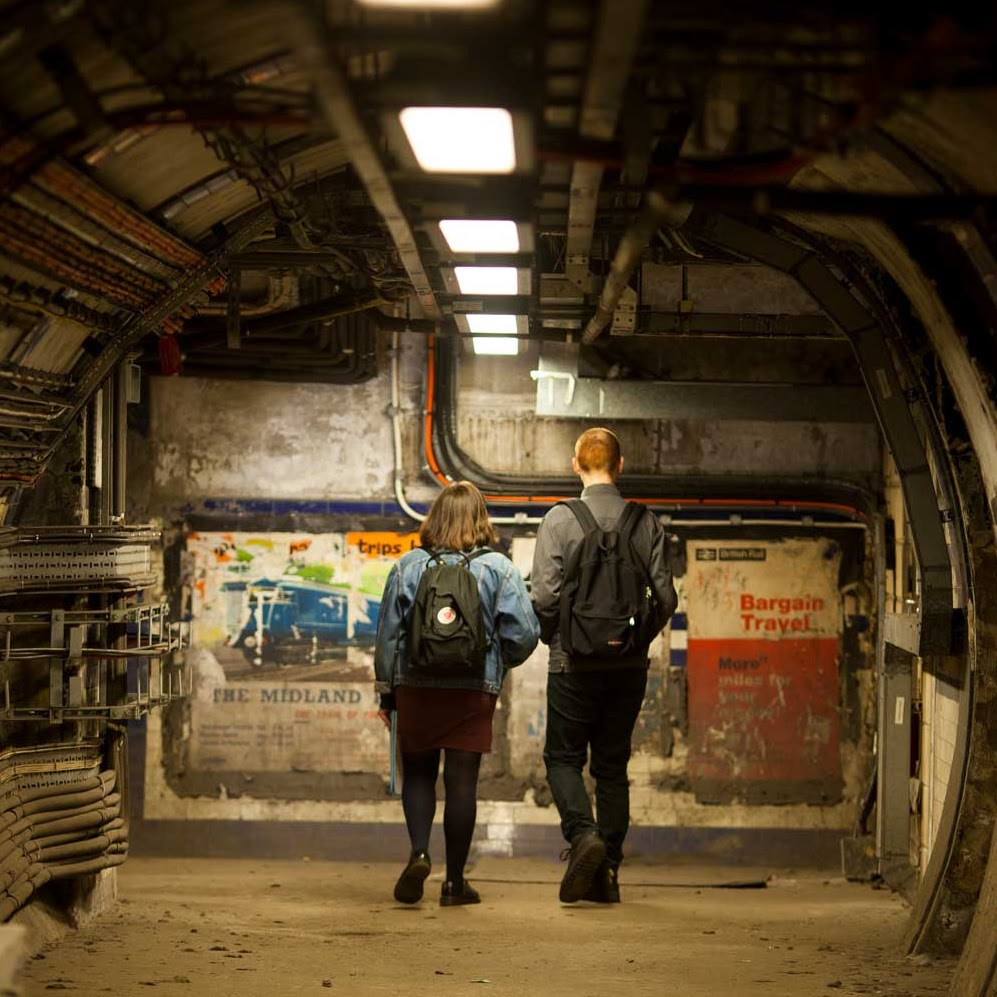 Two people standing in a tunnel looking at posters