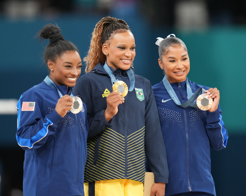 Three woman hold their Olympic medals in front of them.