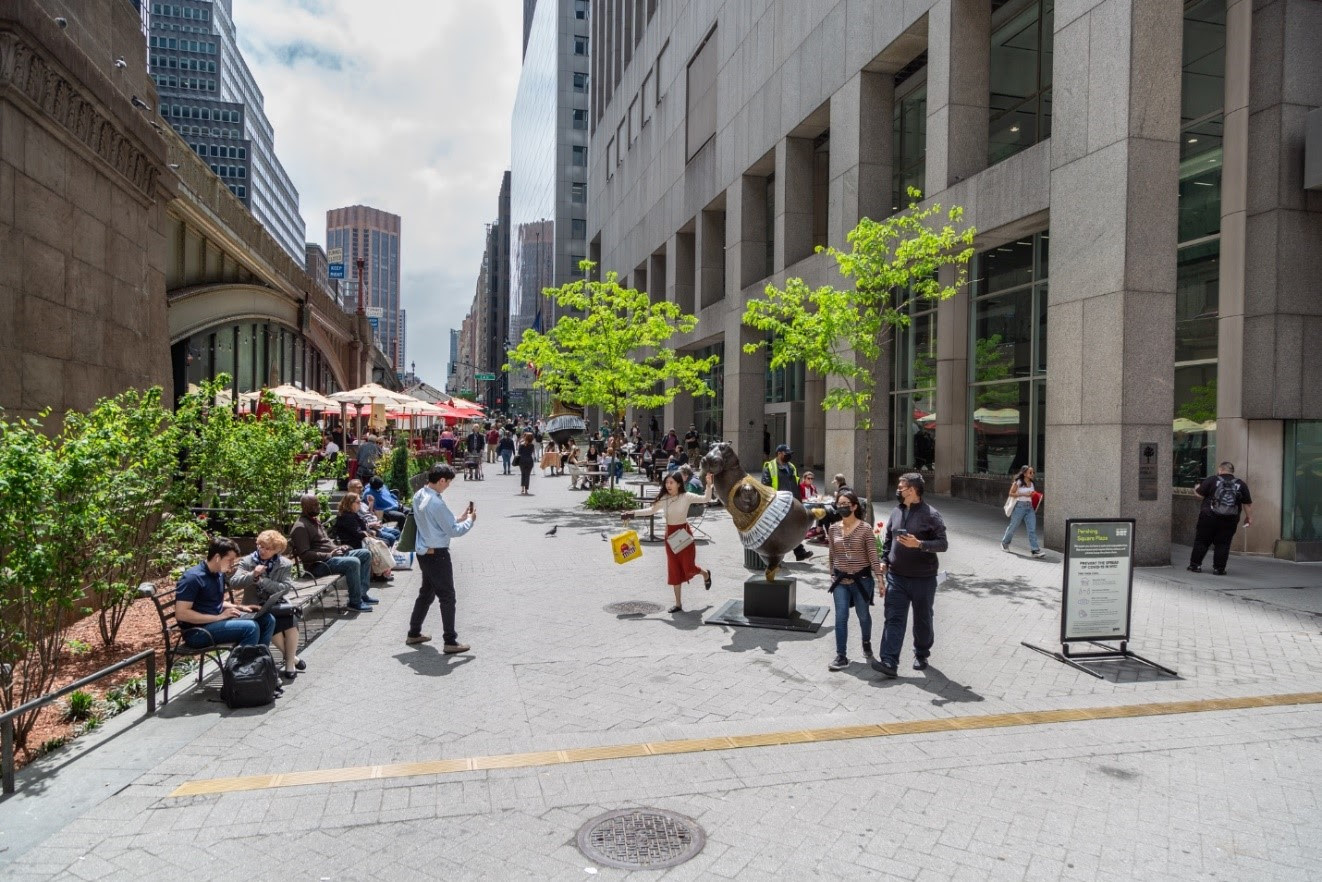 Photo of an outdoor plaza with people sitting, and taking photos.