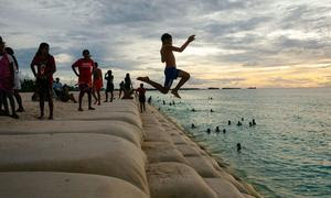 Niños de la isla de Tuvalu, en el Océano Pacífico, juegan en una zona costera protegida por sacos de arena.