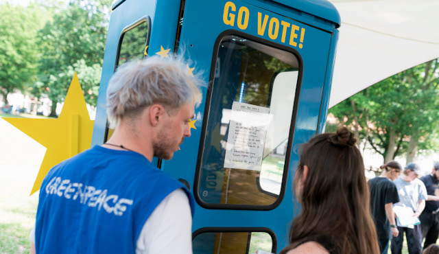 Deelnemers aan een Duits actiekamp gebruiken een telefooncel met de EU-vlag en het opschrift ‘Go Vote!’.