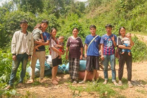 Seven adults and three small children are at the side of a road.