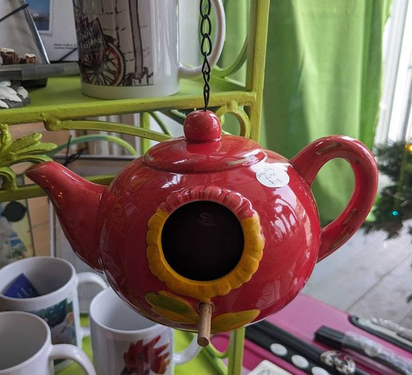 A red teapot style hanging ceramic bird feeder