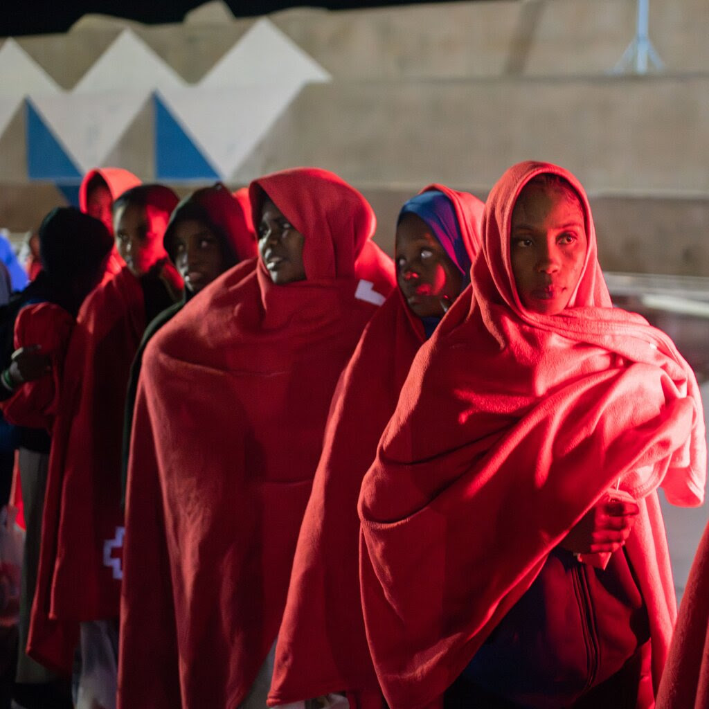 About half a dozen women wearing red head coverings while standing in a line.