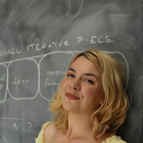 Photograph of a woman leaning against a blackboard