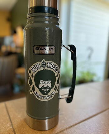 A thermos with a Bob Ross sticker.