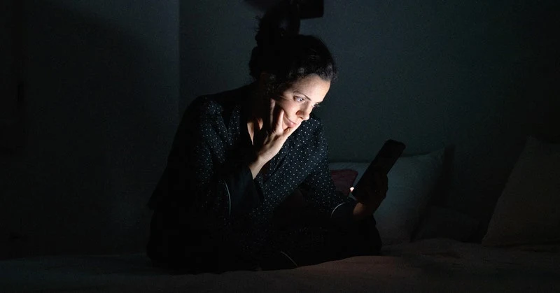 Person using their phone in bed in a dark room