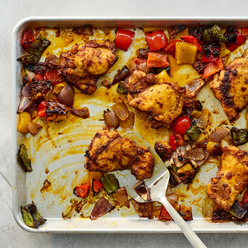 Homemade chicken tikka with vegetables in a silver sheet pan.